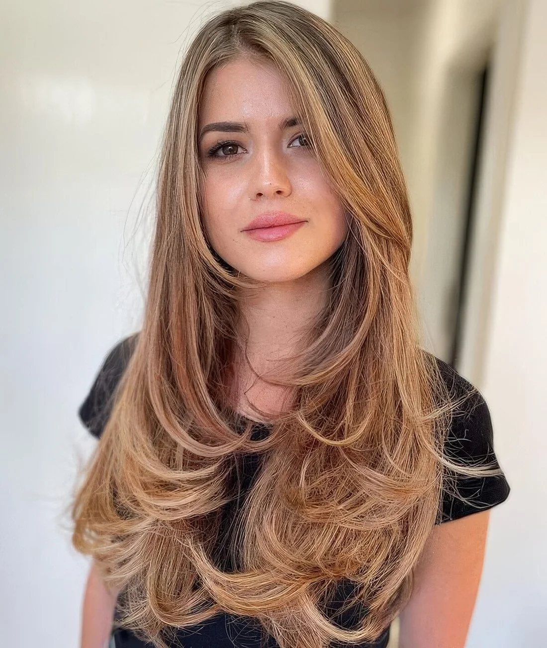 Jaw dropping caramel blonde butterfly cut hair with face-framing layers and rounded ends.