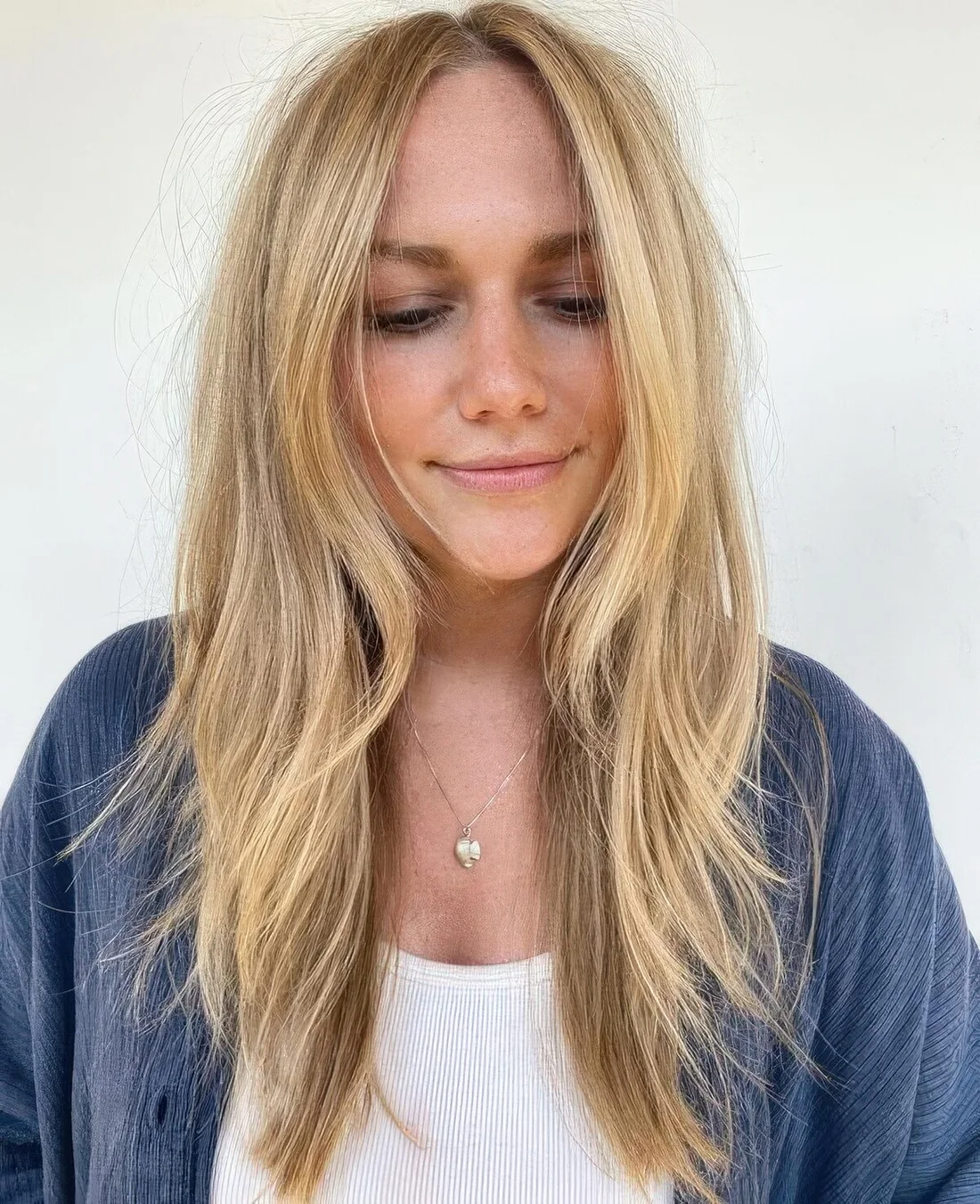 Long and messy blonde hair with layers including face-framing ones, with center part and texture.