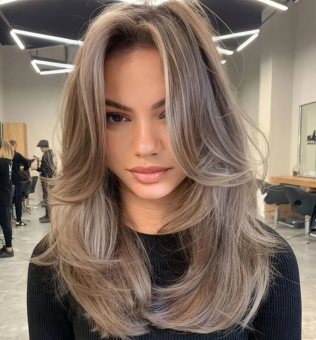 Long mousy brown hair with layers including face-framing ones, with lighter accents and a lot of volume.