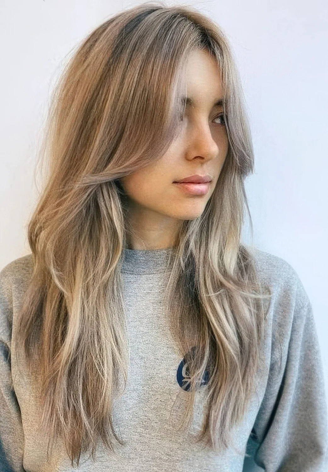 Long mushroom blonde hair with a slight balayage and long layers framing the face that perfectly frame the face.