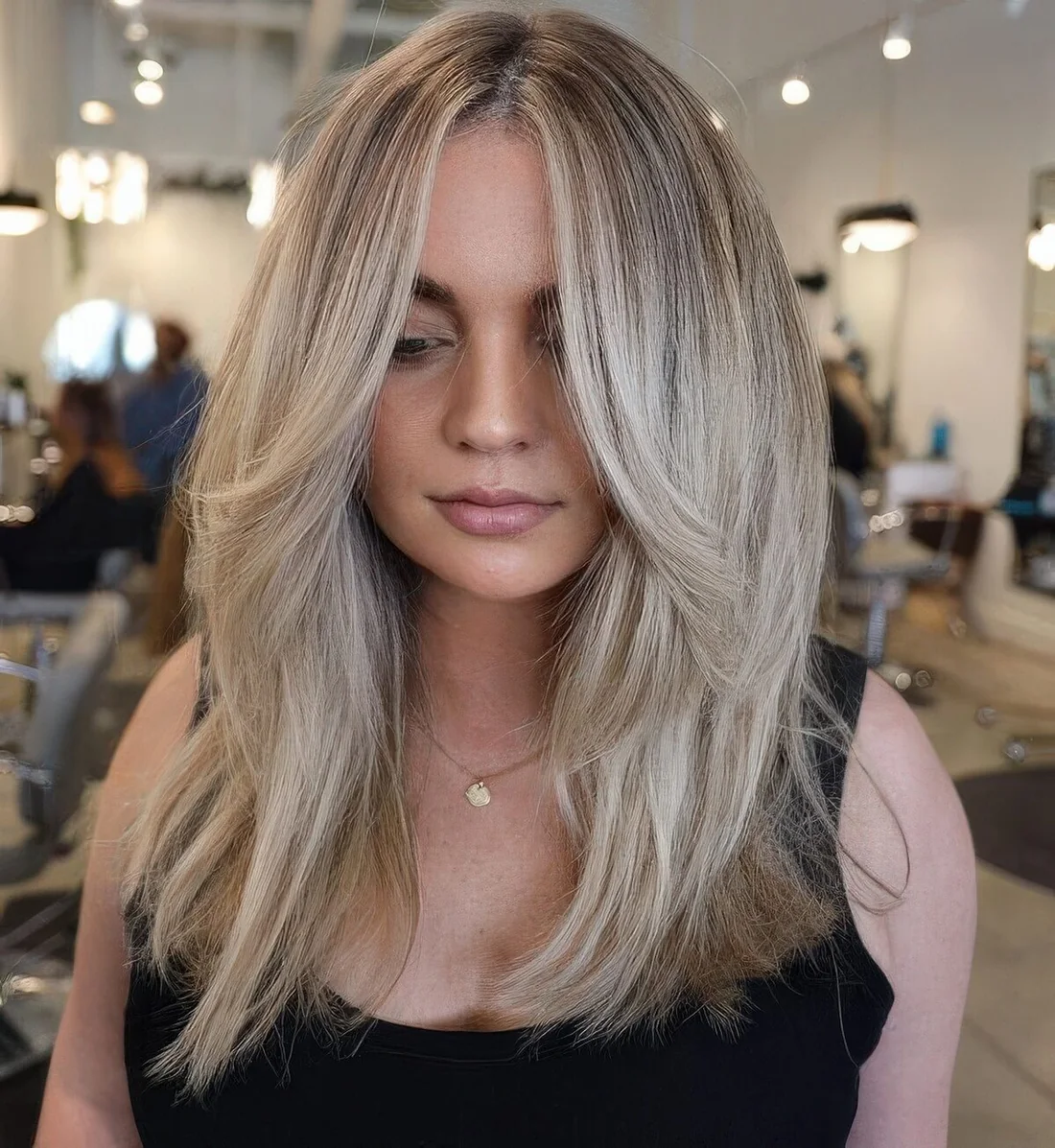 Long blonde hair done in a cold shade, with face-framing layers and center part to accent the face.