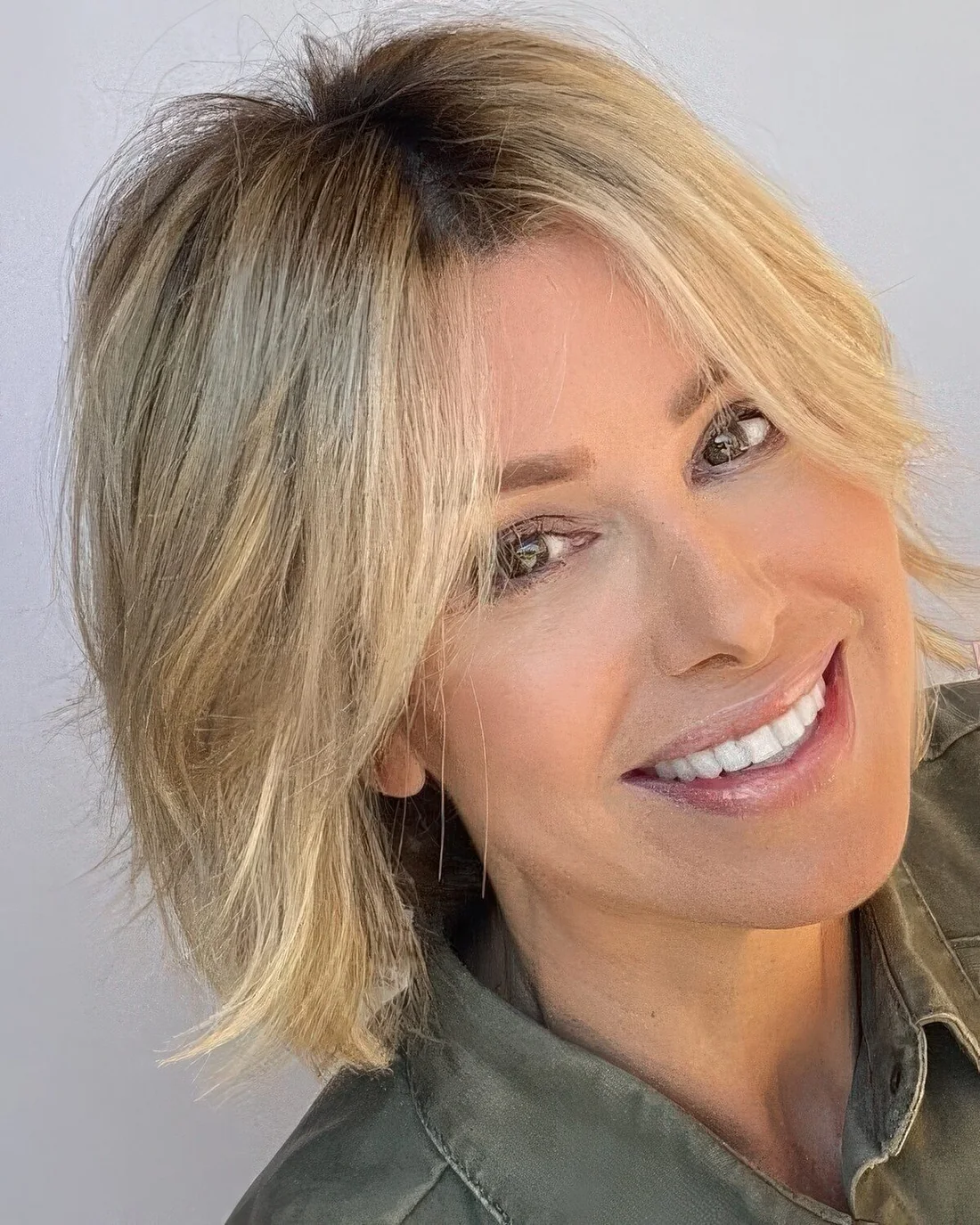 Blonde midi feathered bob with a darker root and texture.