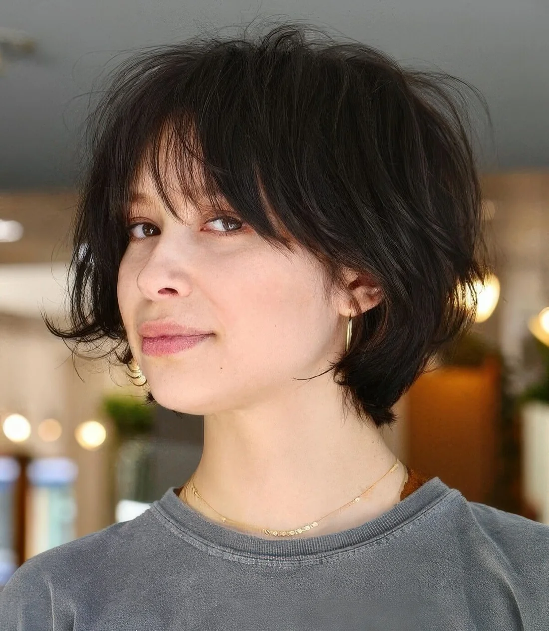 Dark brown feathered short bob with wispy bangs.