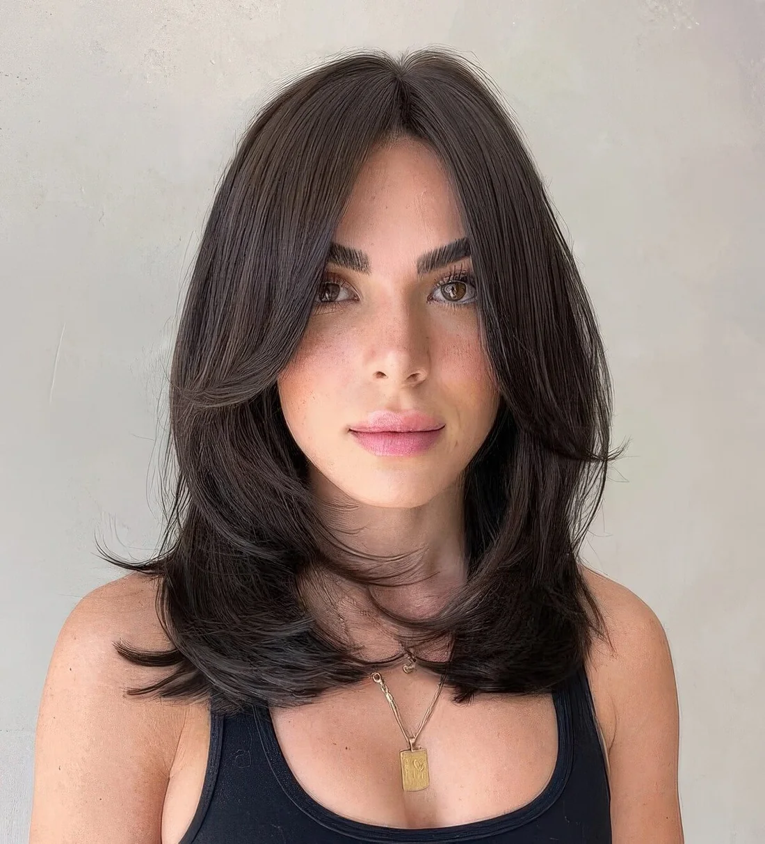 Shoulder-length butterfly haircut with bangs.