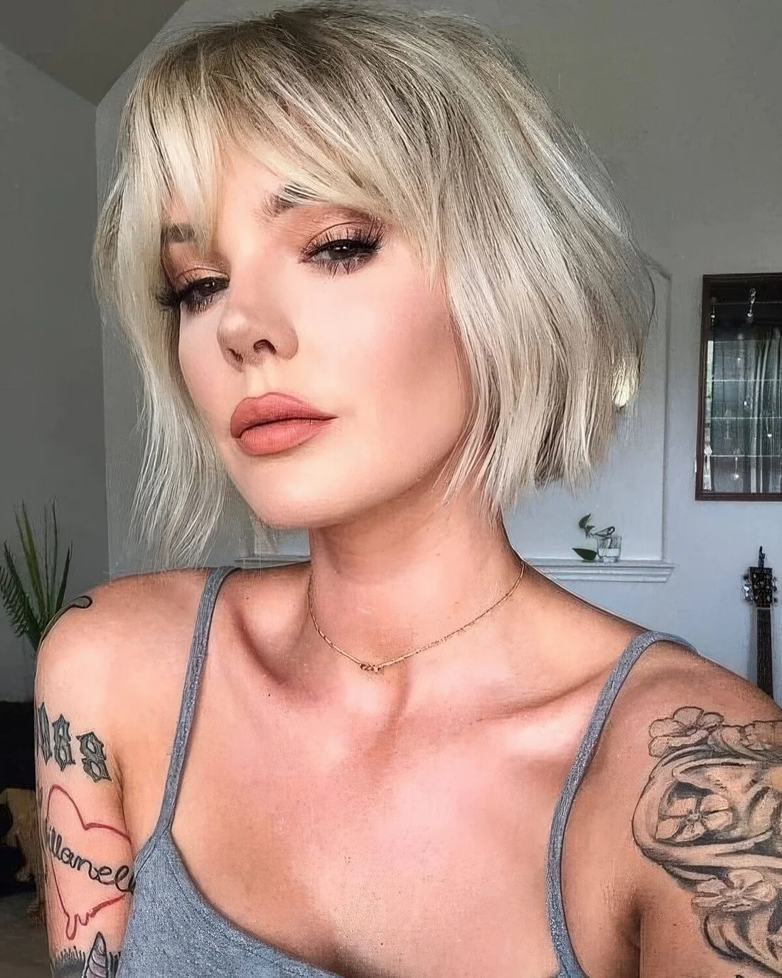 Blonde French bob with waves and bottleneck bangs.