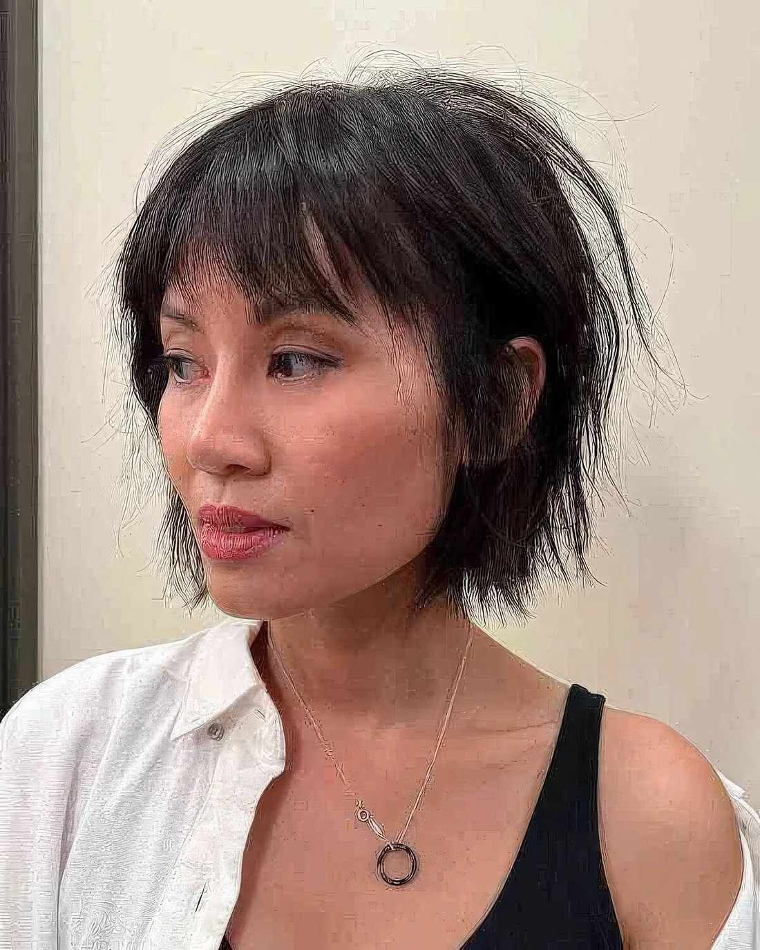 Choppy French bob in black, with wispy bangs.