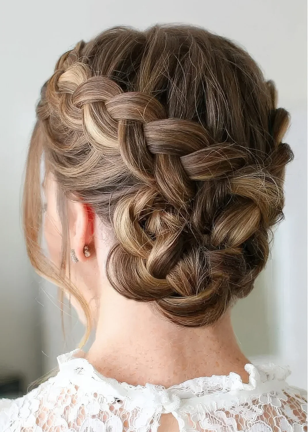 French braid updo with a bump on top and face-framing hair.