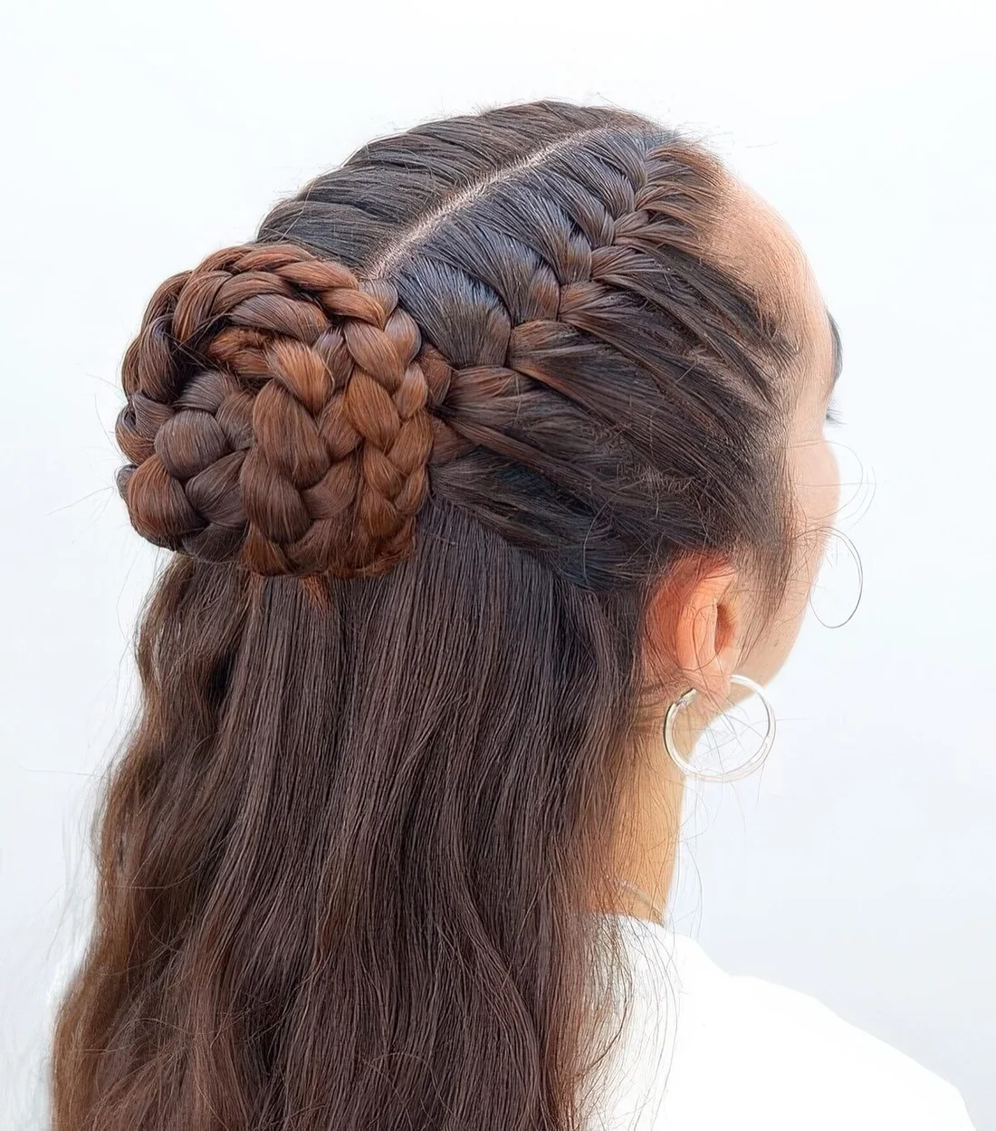 Unique half updo with two French braids, a top bun and waves down.