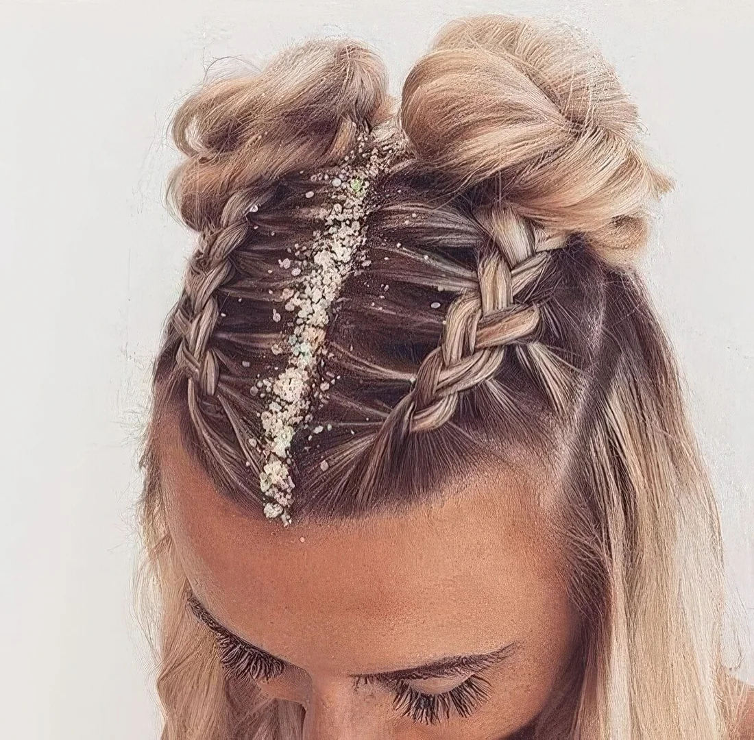 Party hairstyle with two top French braids and space buns plus hair down and glitter on the parting.