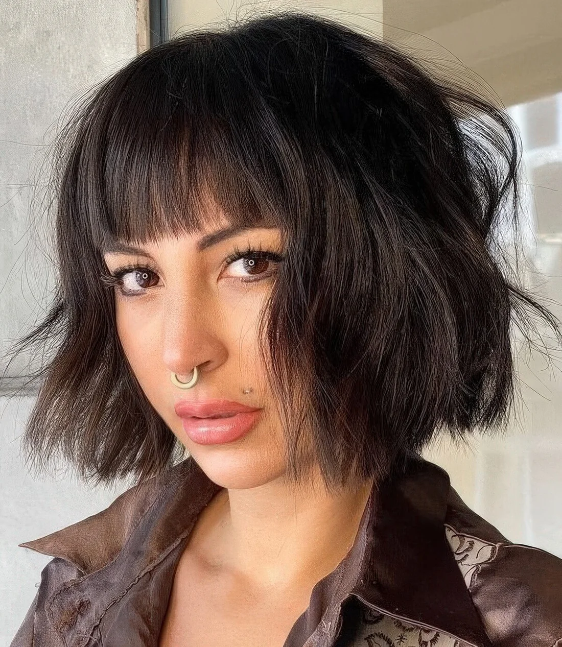 Black textural and wavy chin-length bob with waves and blunt bangs.
