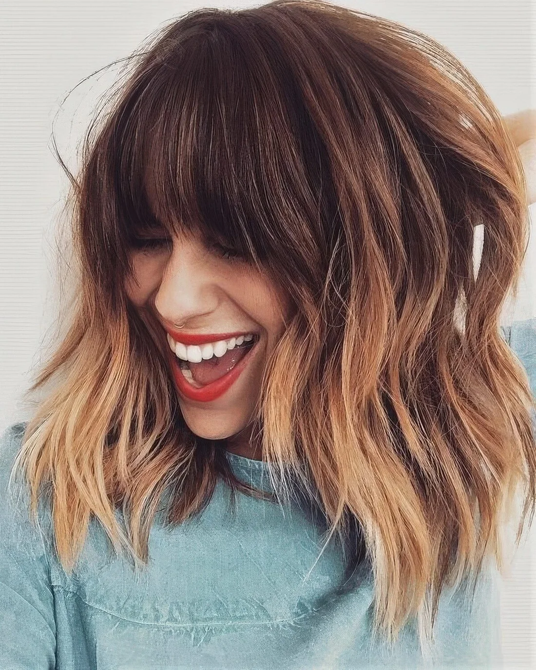 Brown layered long bob with copper highlights and with classic fringe bangs.