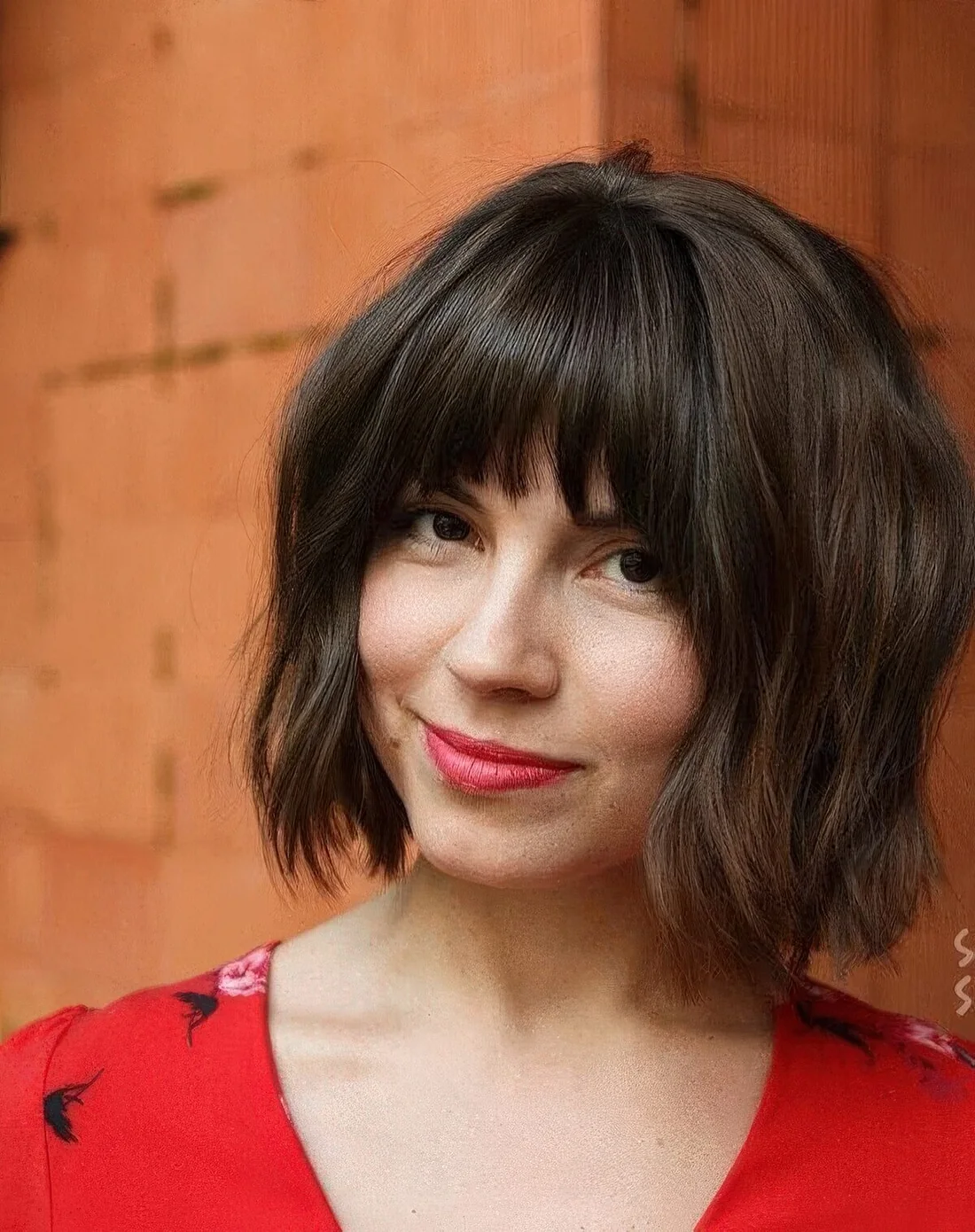 Dark brown chin-length bob with caramel highlights and fringe bangs.