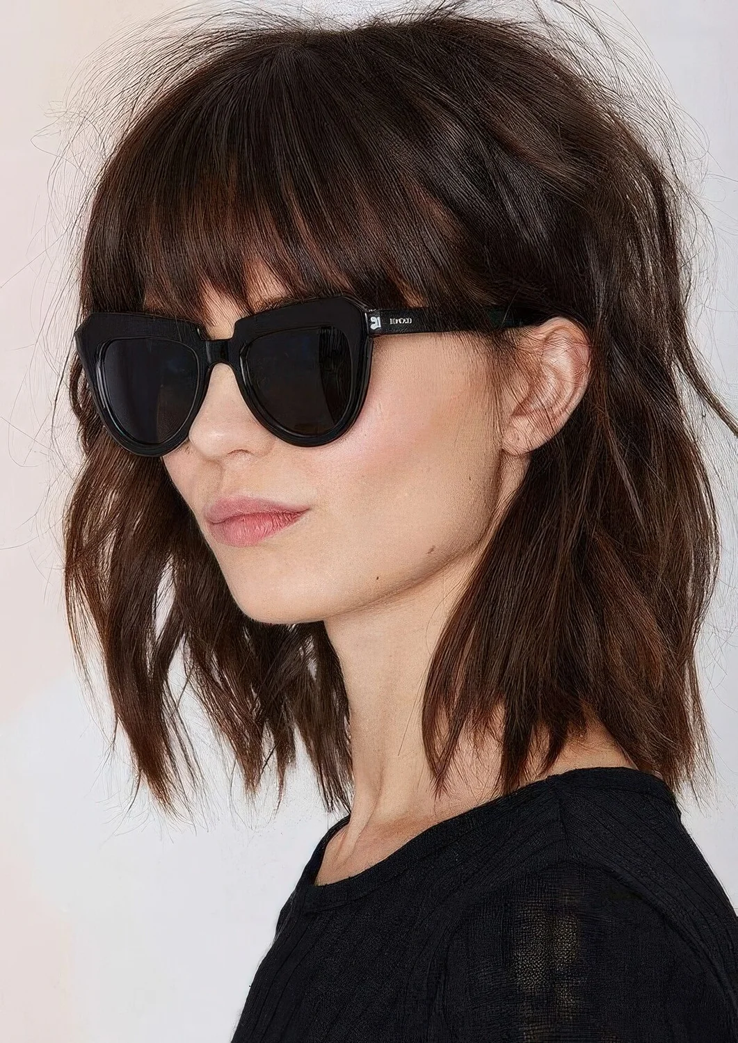 Shaggy brown shoulder-length bob with classic bangs and messy waves.