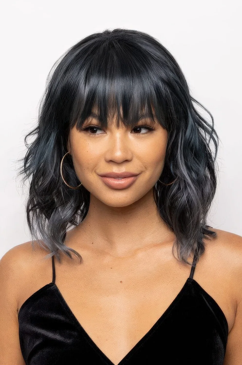 Black wavy hair with an ombre touch and fringe bangs.