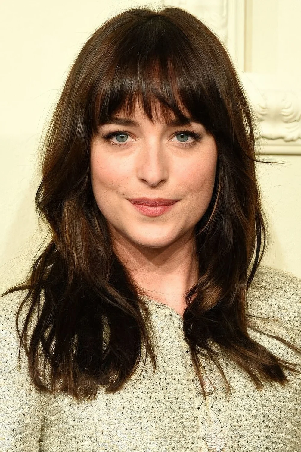 Dakota Johnson wearing long dark brunette hair and fringe bangs.