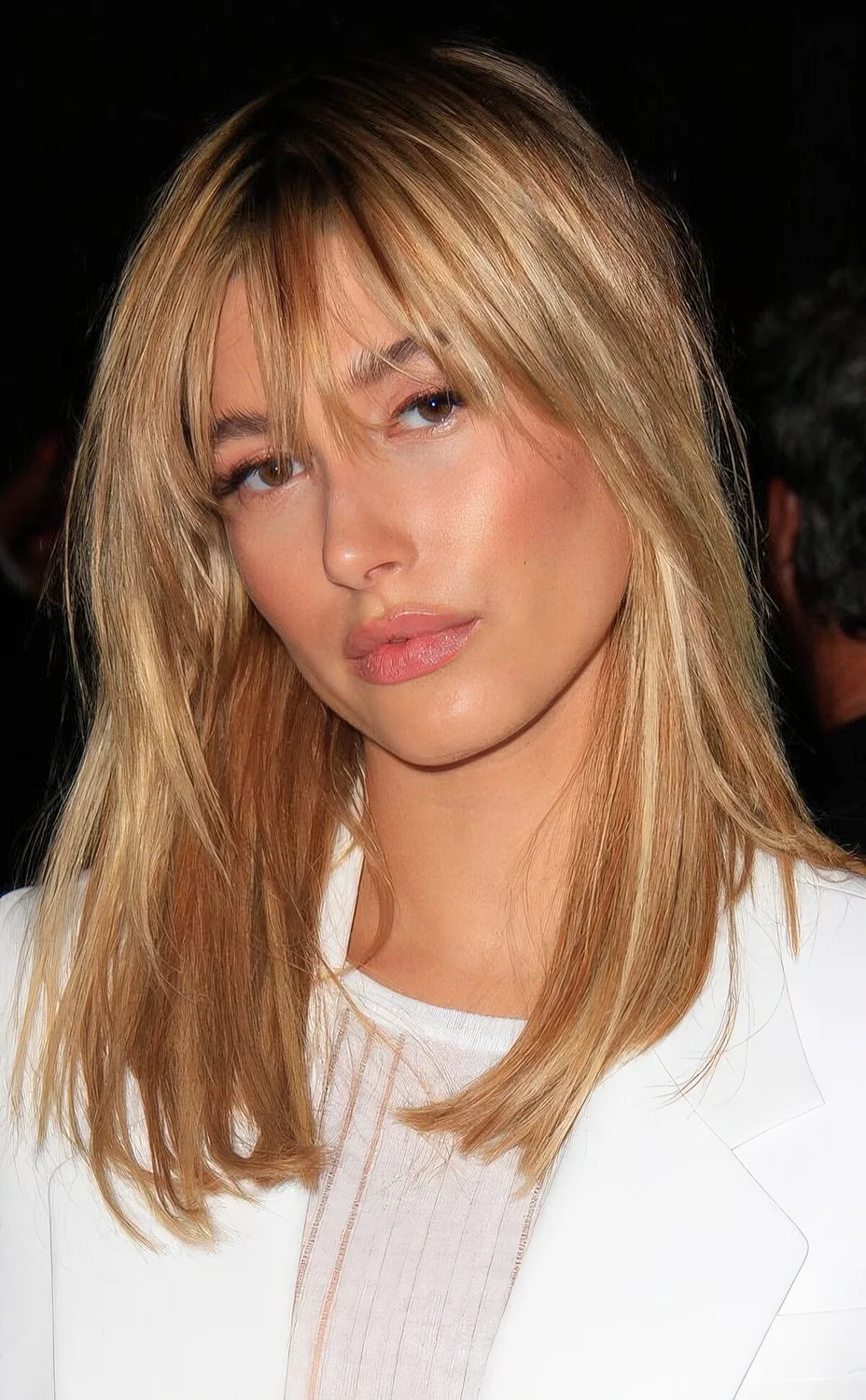 Hailey Bieber wearing golden blonde medium-length hair and outgrown fringe bangs.
