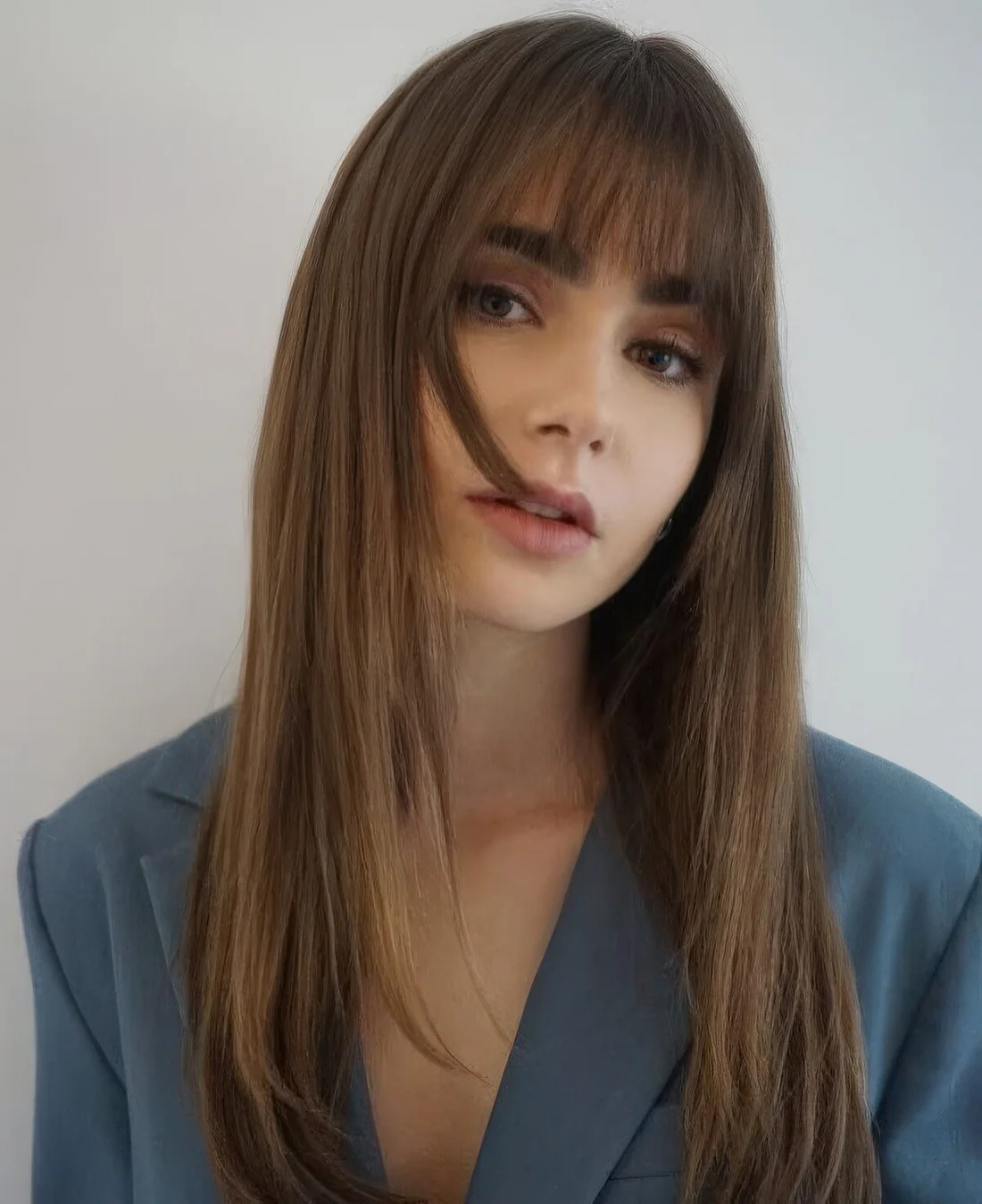Lily Collins wearing long brunette hair with classic fringe bangs.