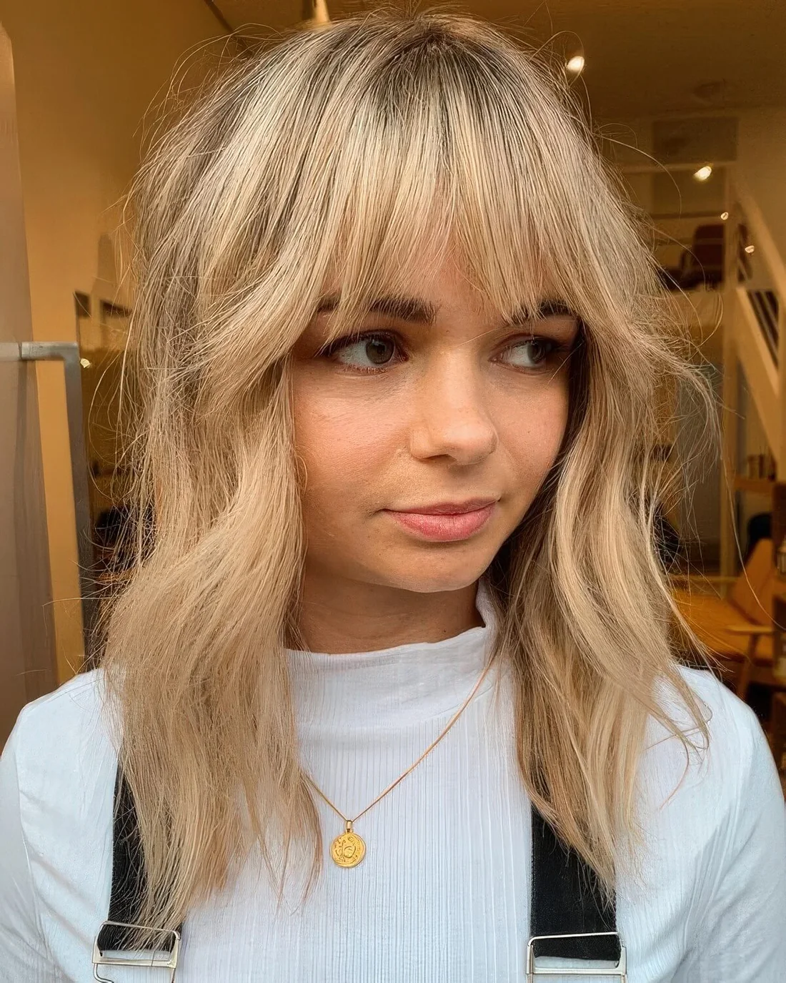 Long and textured blonde hair with waves and fringe bangs.