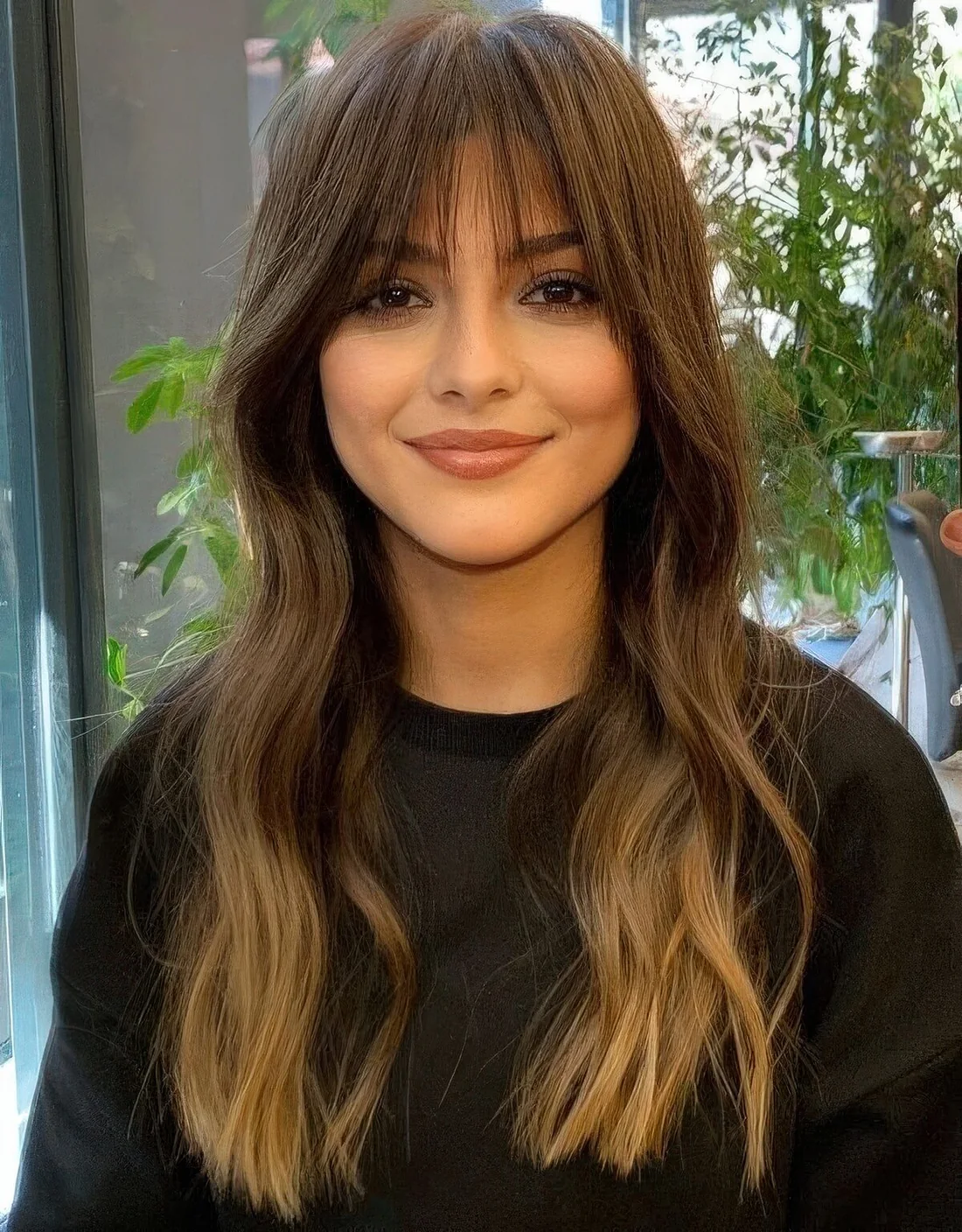 Long brunette wavy hair with an ombre touch and fringe bangs.