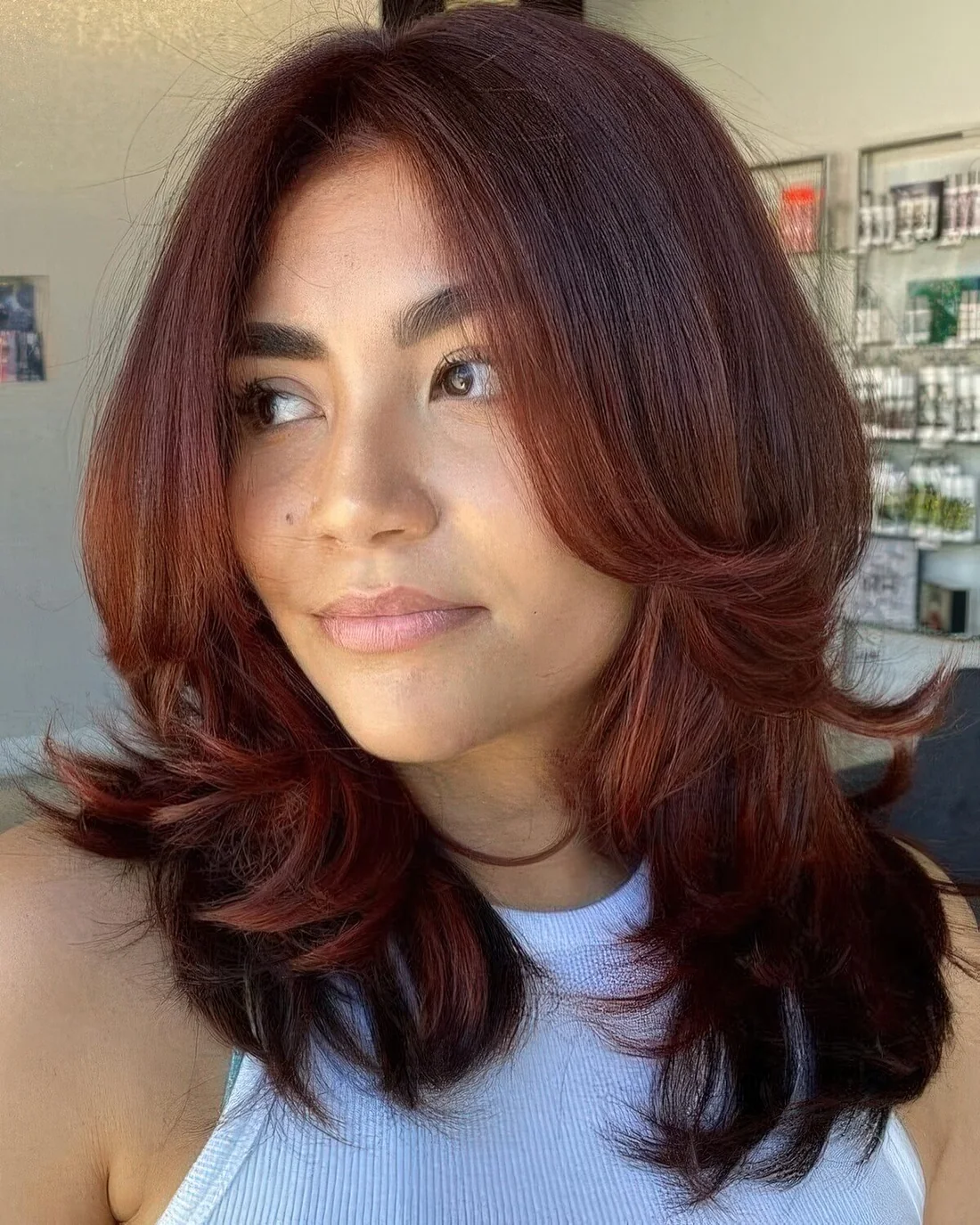 Auburn medium-length butterfly haircut with curved ends.