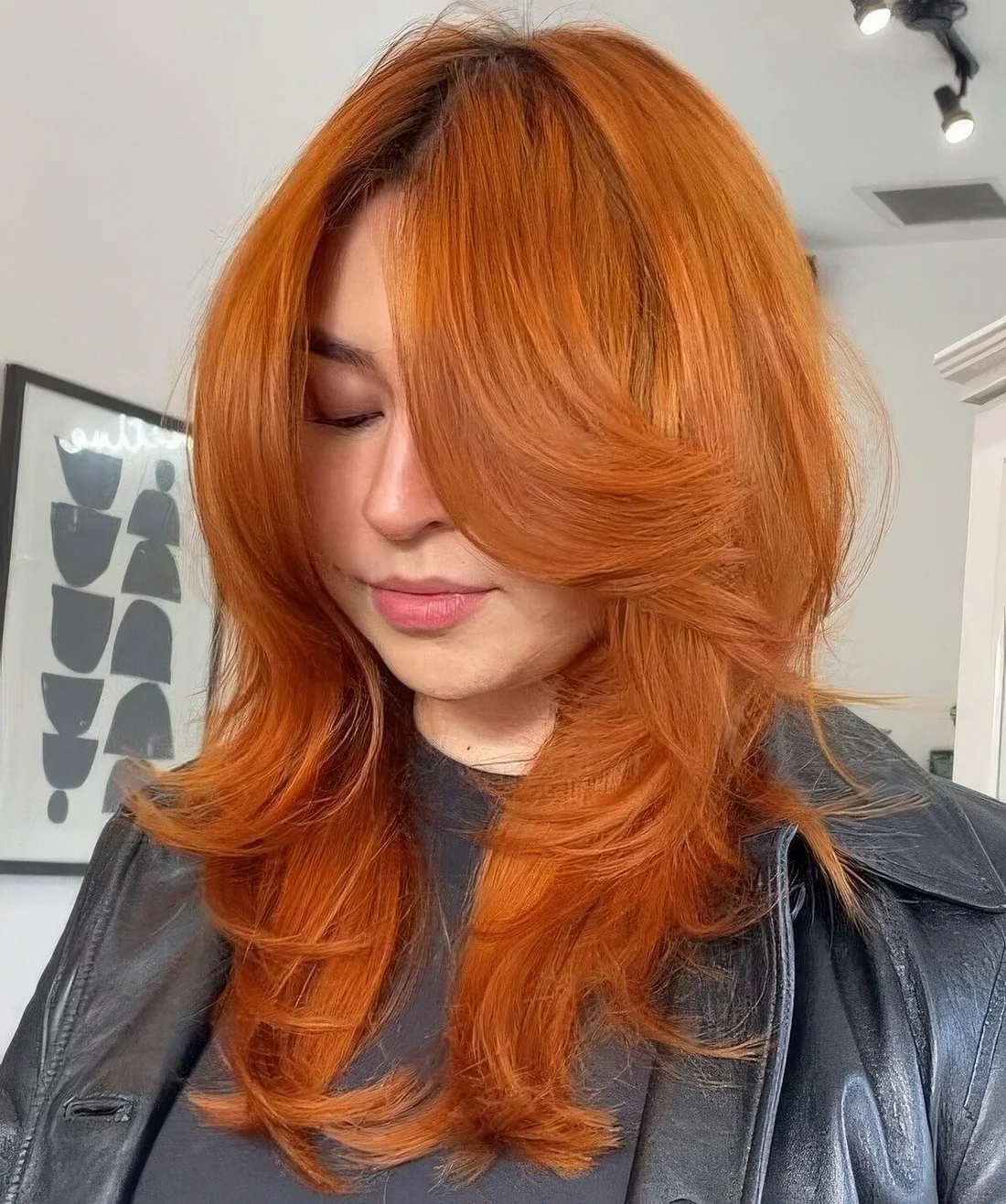 Ginger butterfly haircut of medium-length, with bottleneck bangs and curled ends.