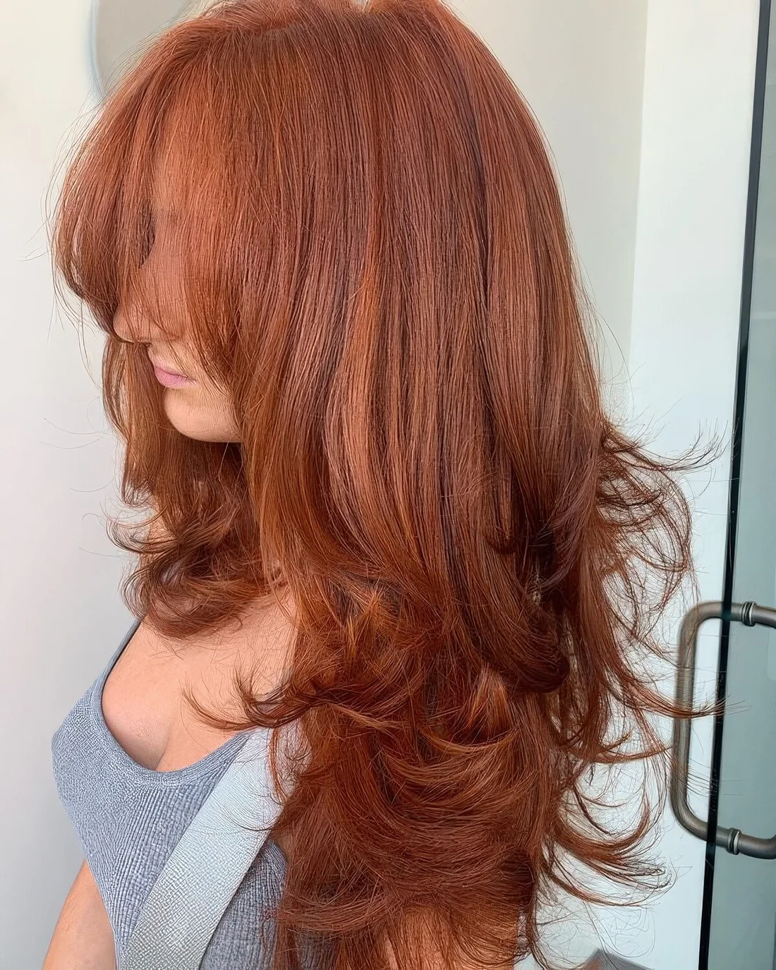 Breathtaking long red butterfly haircut with a lot of volume, wispy bangs and curled ends.