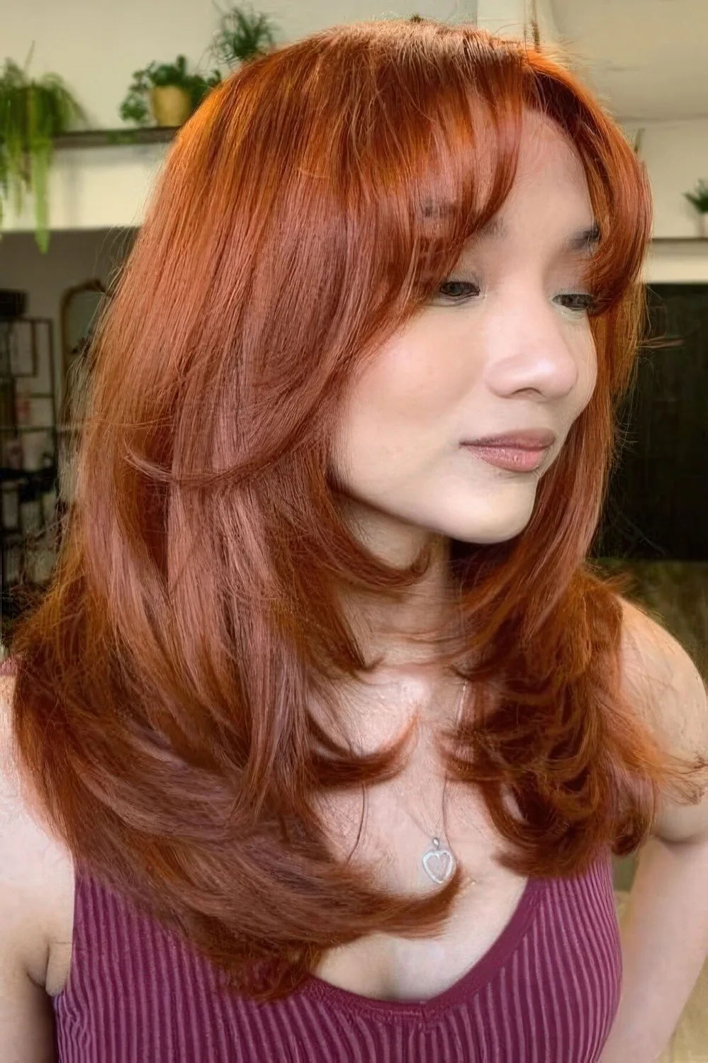 Copper butterfly haircut with bottleneck bangs and wavy ends plus a lot of volume.