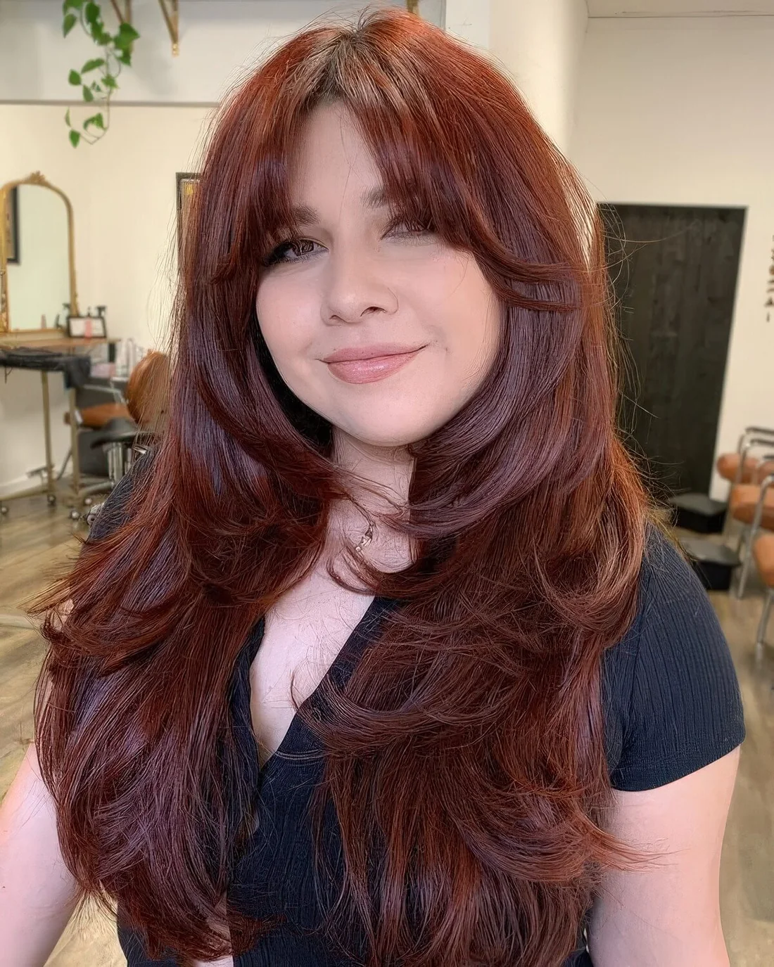 Auburn long butterfly haircut with curtain bangs, curled ends and a lot of volume.