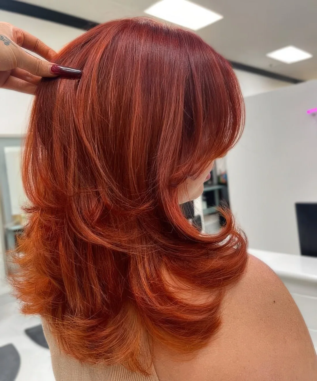 Medium butterfly haircut done in super bold red shades, with highlights and curled ends.