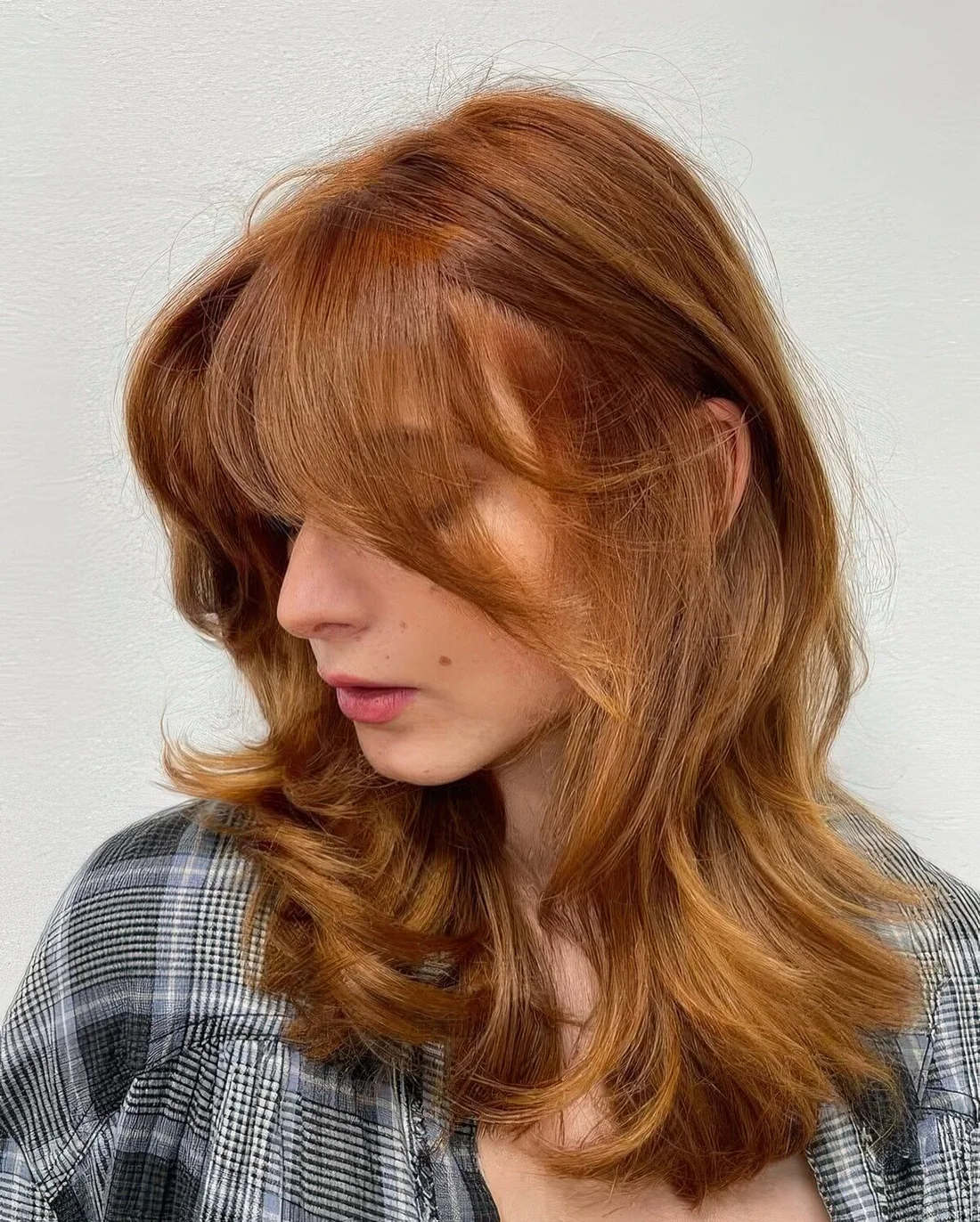 Medium butterfly haircut with some golden blonde highlights done in a super bold ginger color, it.