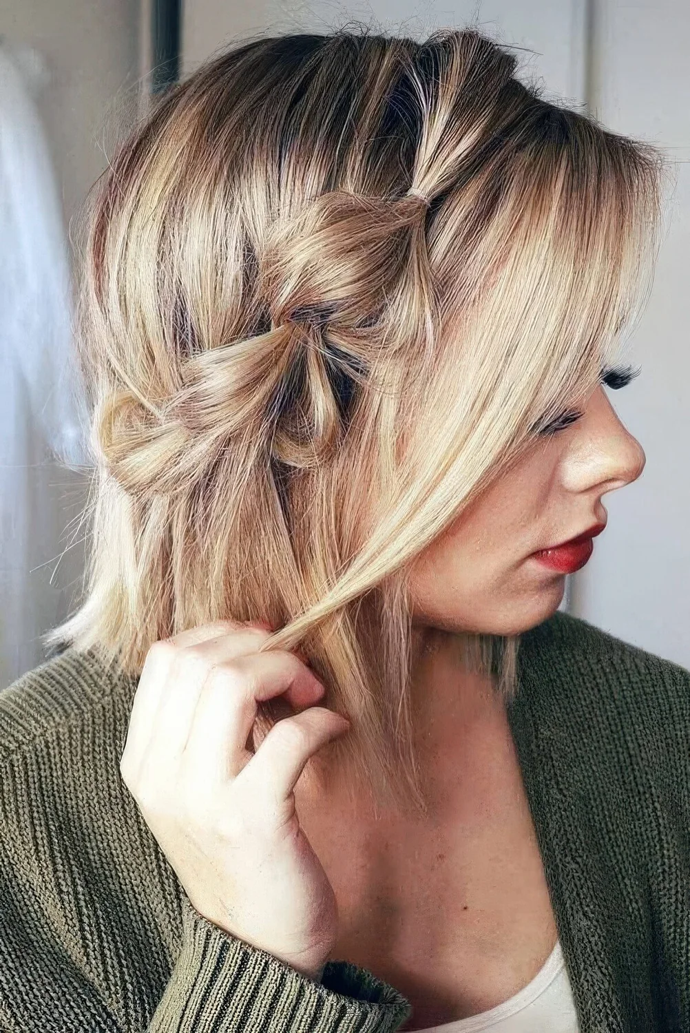 Blonde bob with a bubble side braid and some locks framing the face.