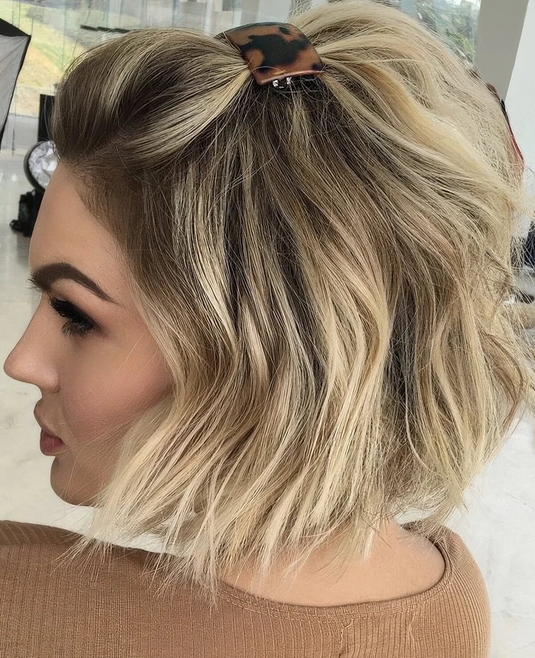 Chin-length bob styled as a half updo with some hair up secured with a barrette and waves down.