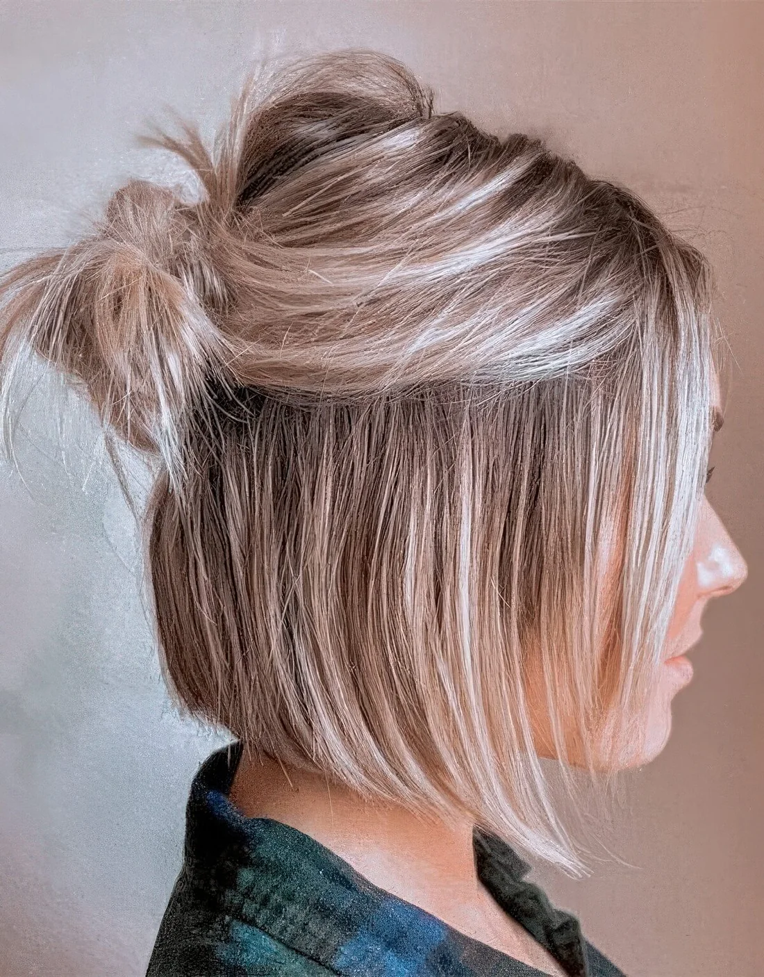 Long bob styled as a half updo with a messy bump and a small knot plus face-framing hair.