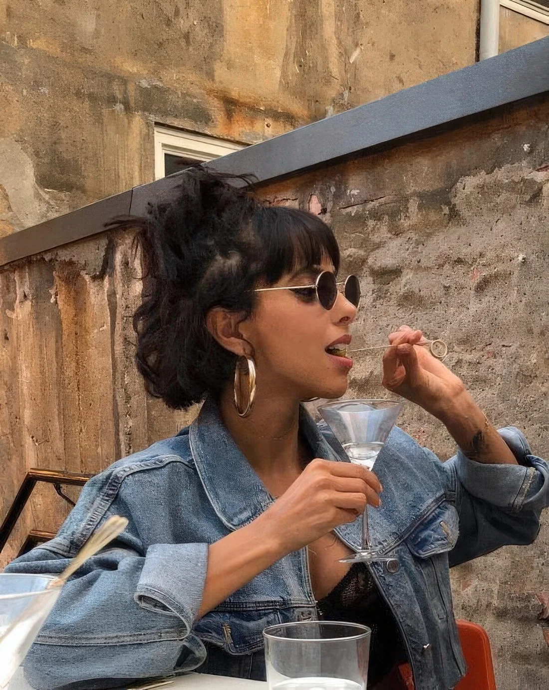 Midi bob styled as a half updo with a mess top knot, bottleneck bangs and wavy hair down.