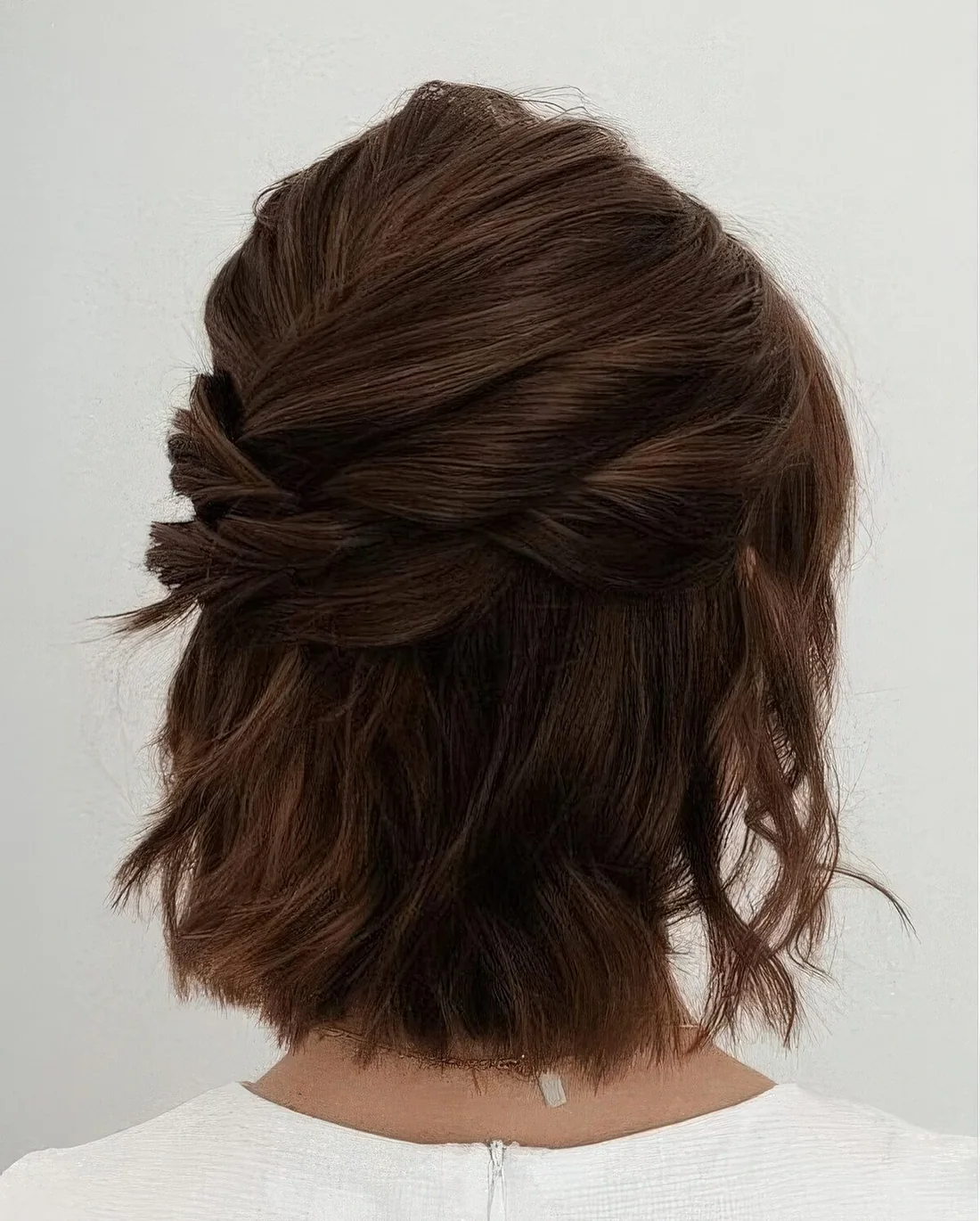 Modern half updo with several twists on top and a bump, with some waves down.