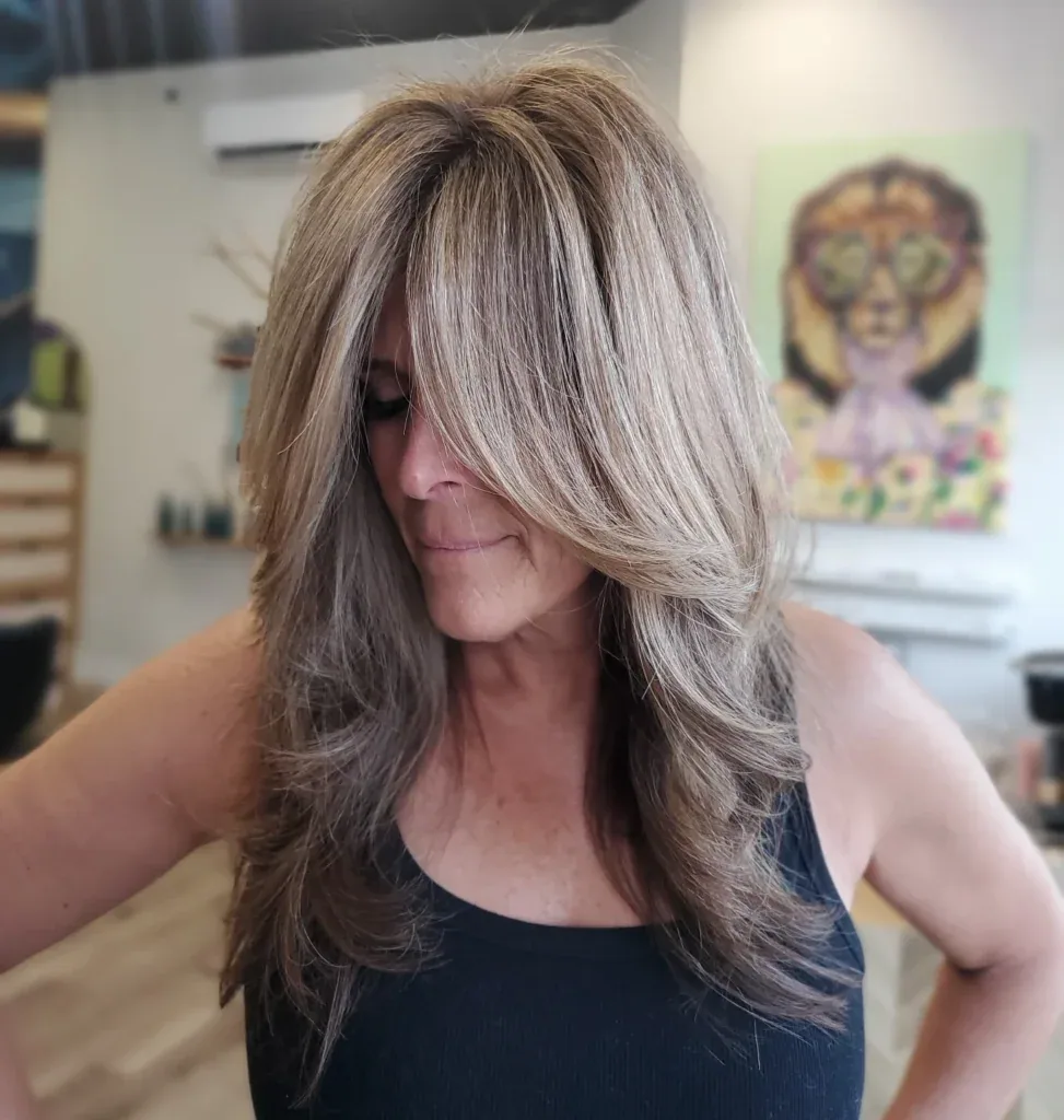 chest wavy blonde layers with curtain fringe shown as a hairstyles for women over 40 with bangs idea