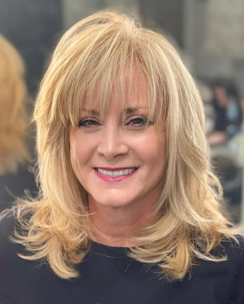 shoulder wavy blonde layers with wispy fringe shown as a hairstyles for women over 40 with bangs idea