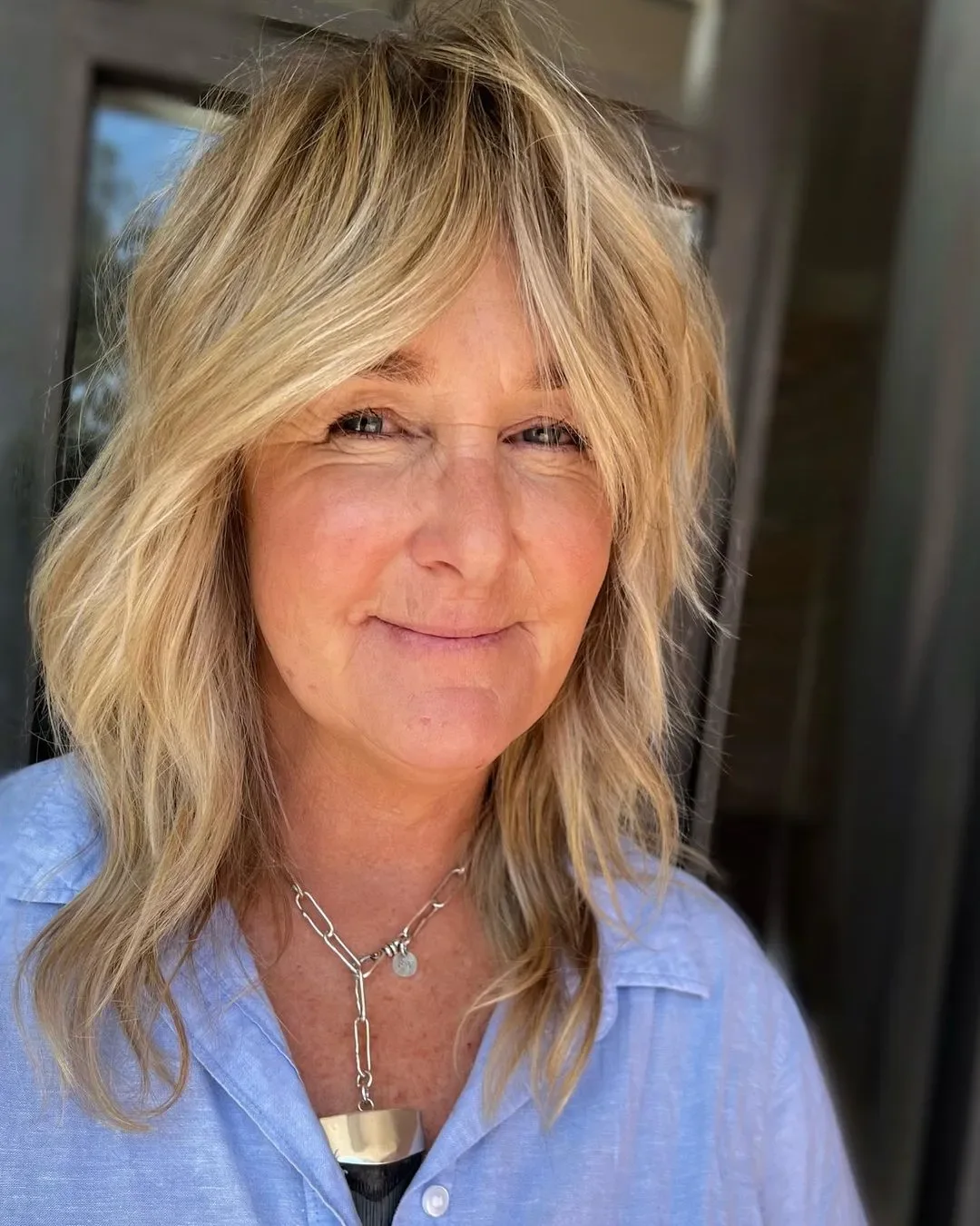 shoulder wavy blonde shag with curtain fringe shown as a hairstyles for women over 60 idea