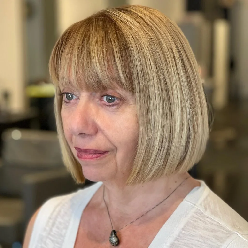 chin straight blonde bob with wispy fringe shown as a hairstyles for women over 60 idea