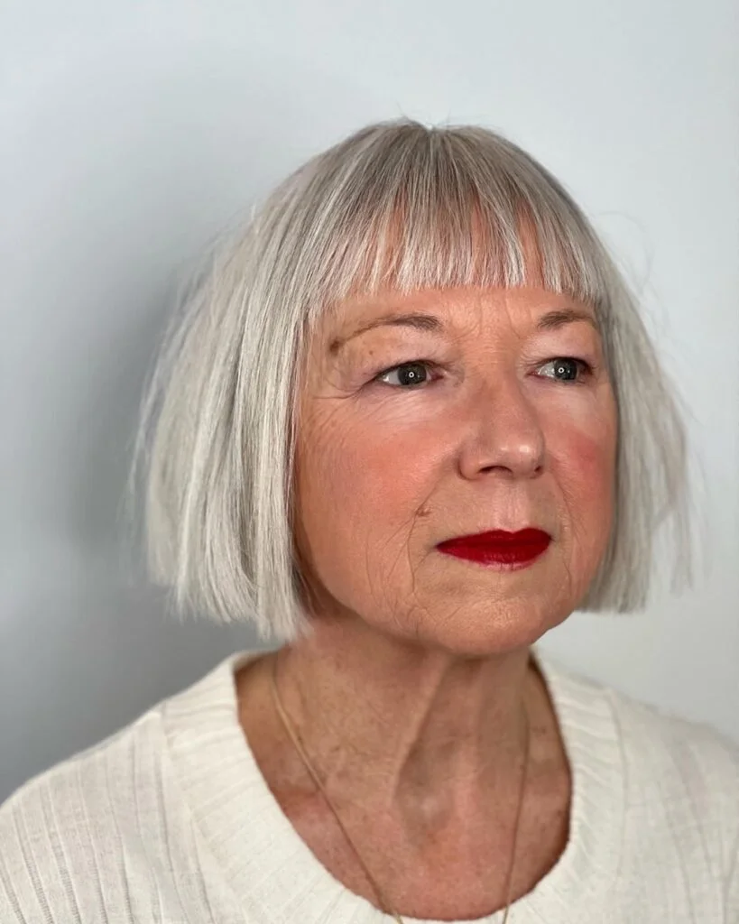 chin straight silver bob with blunt fringe shown as a hairstyles with bangs for older women idea