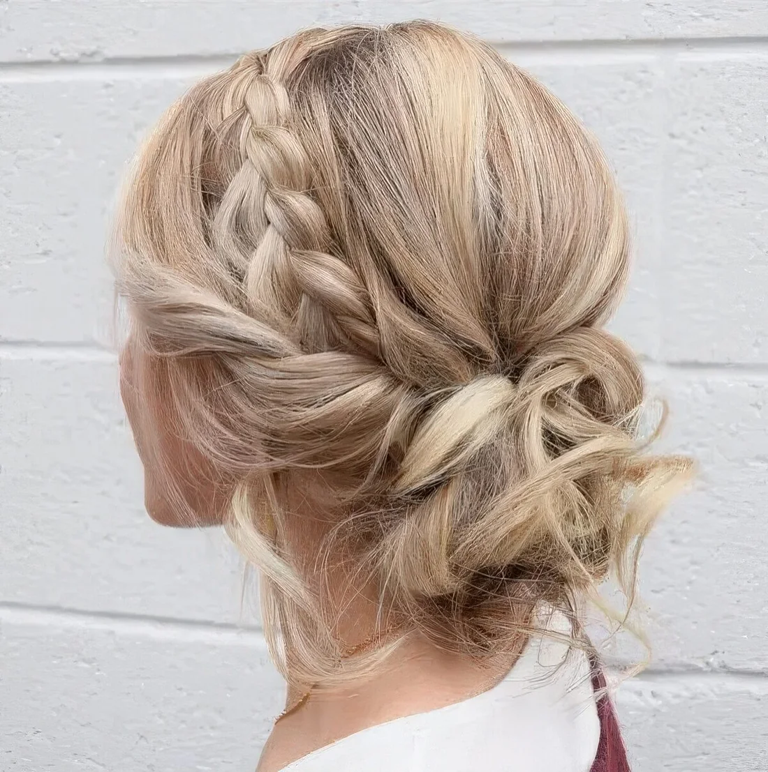 Messy and curly low updo with a braided halo and some locks and curls down for an effortlessly chic look.