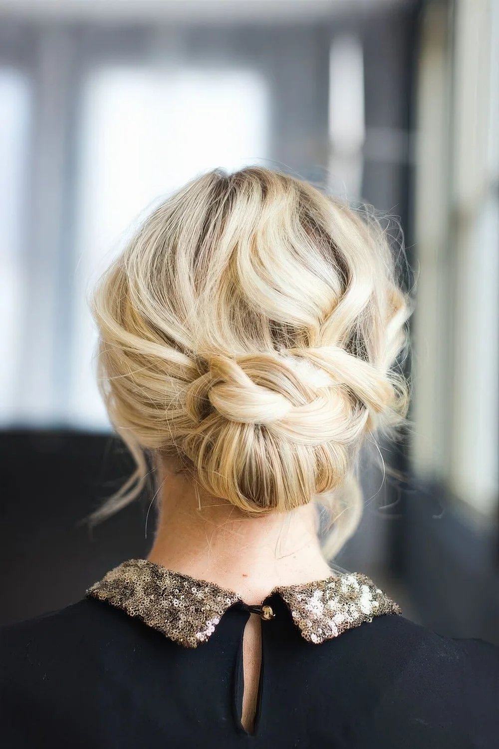 Low updo with a braided touch and a wavy and mess top.
