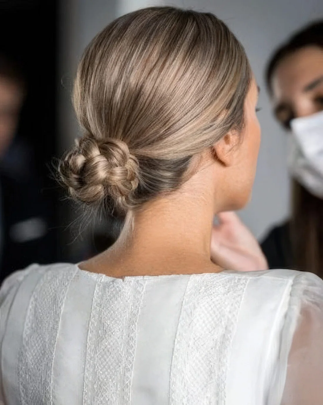 Photo showing braided low bun with a sleek top, with the hairstyle clearly visible.