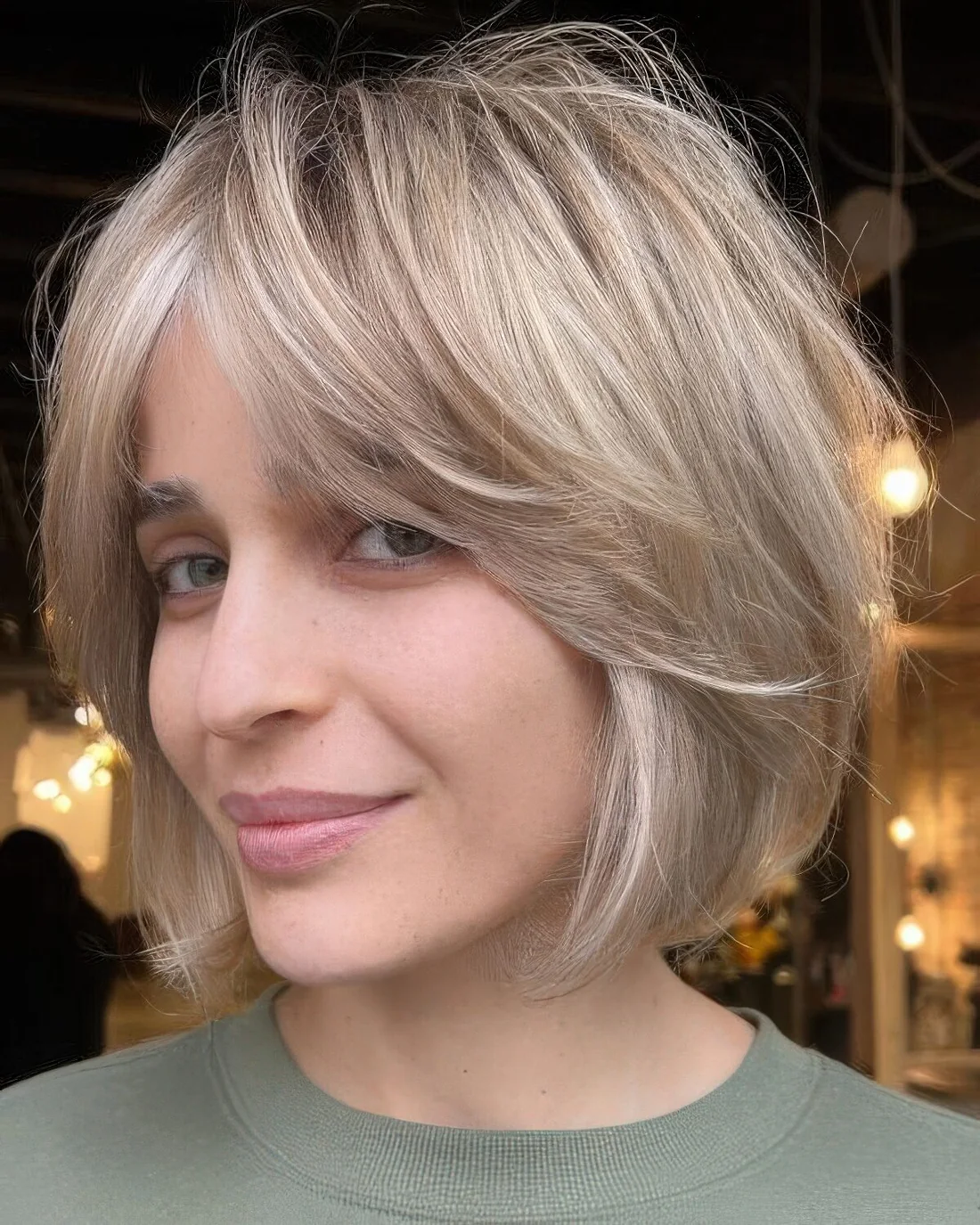 Cold blonde feathered chin-length bob with curtain bangs.