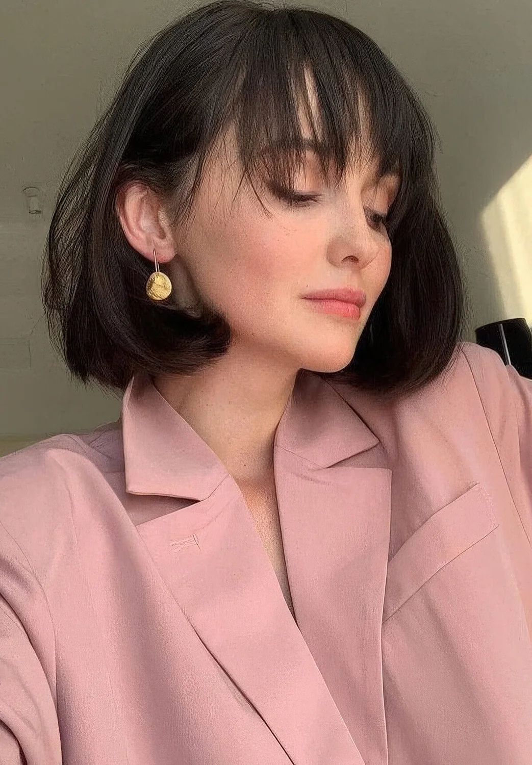 Medium black bob with rounded ends and wispy bangs that accent the eyes and the face.