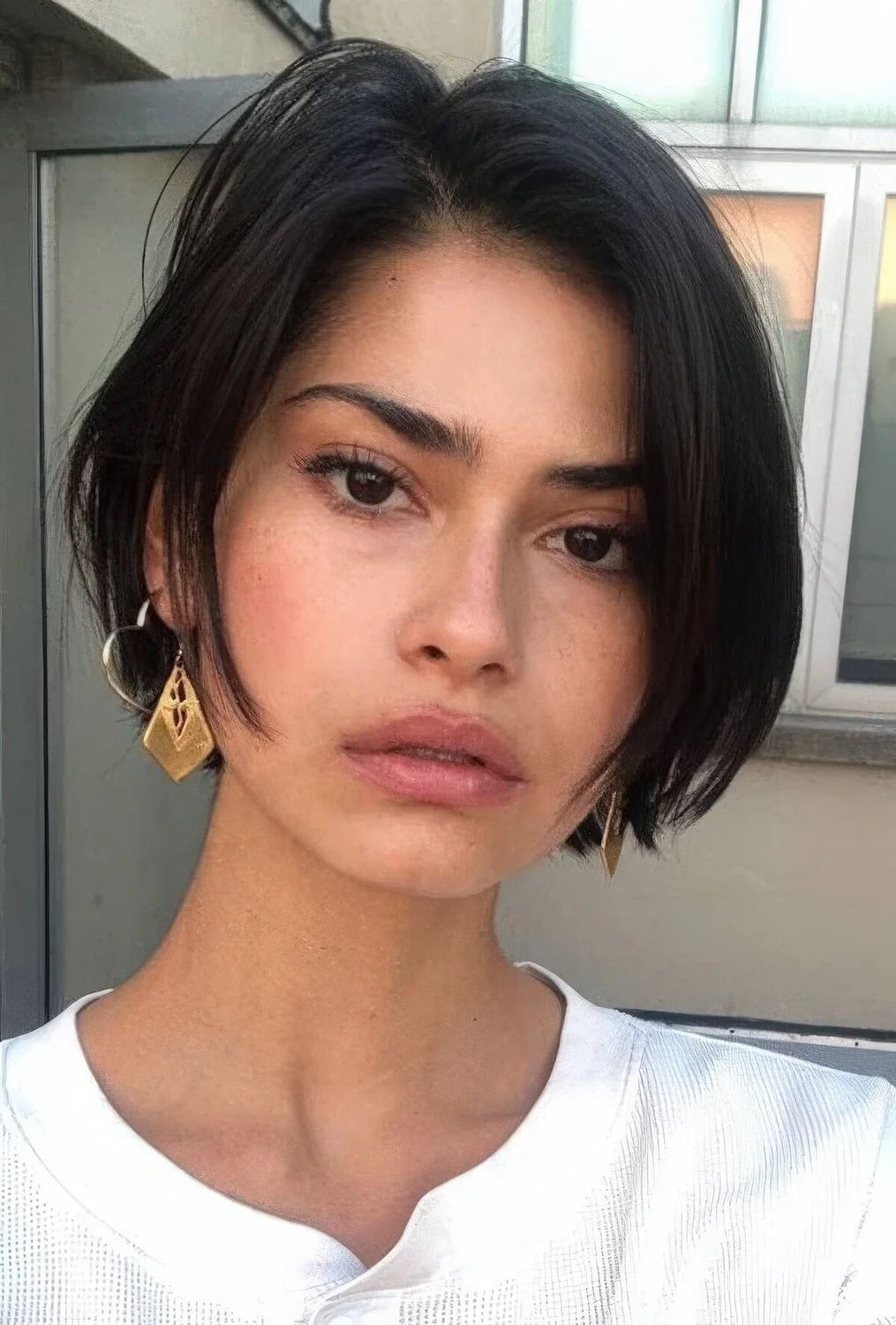 Rebellious French bob hairstyle in black, with side part and a bit of shaggy touches.