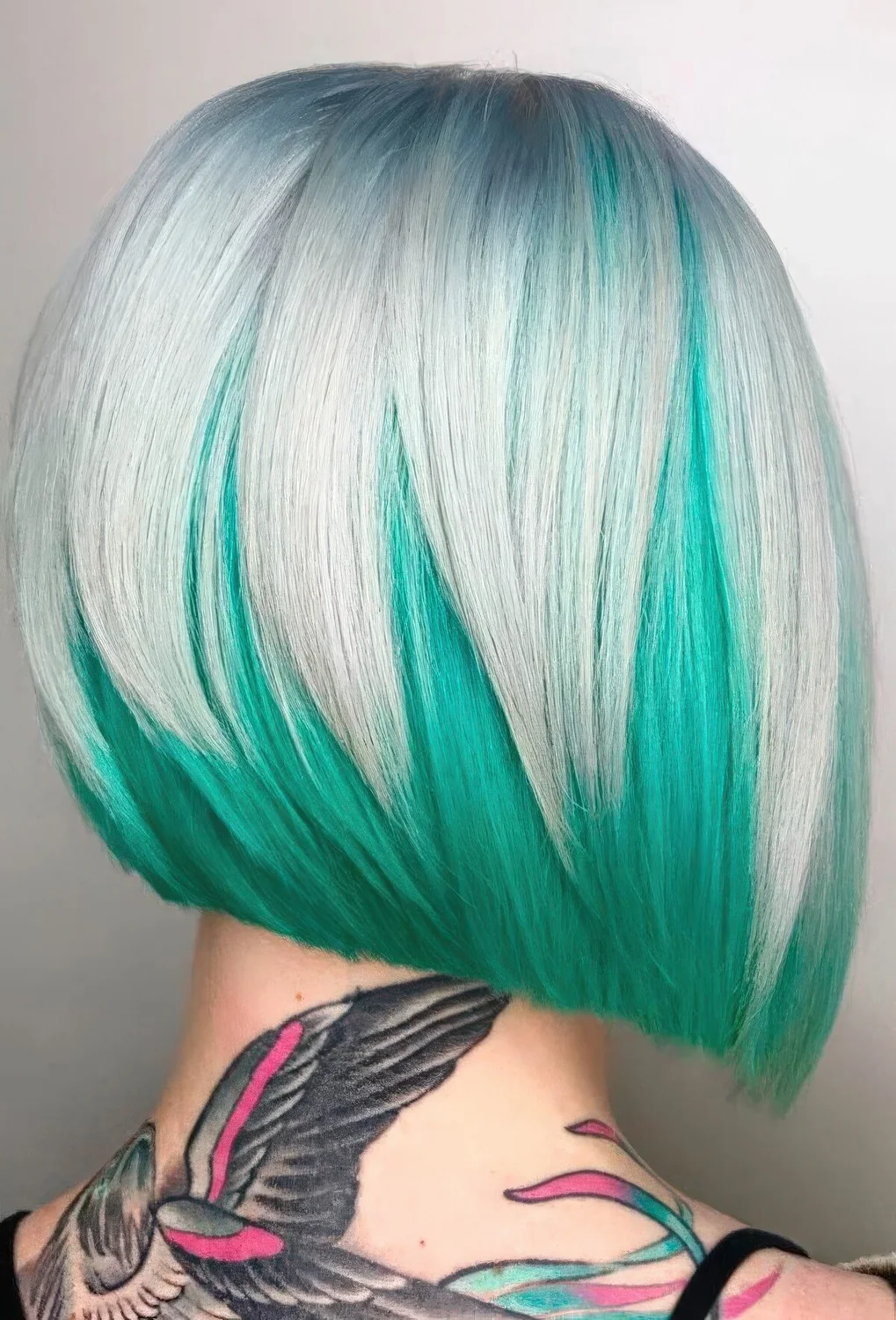 Stacked and layered bob with bold color, with a light blue root going to icy blonde and then to emerald.