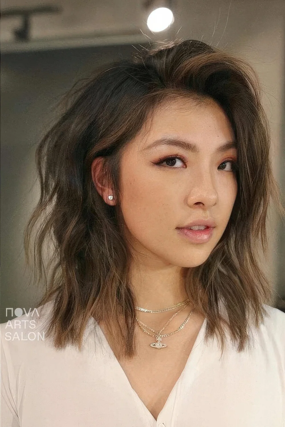 Dark brunette layered long bob with caramel balayage and side part, with a lot of volume and texture.