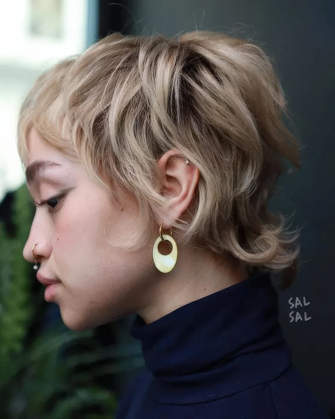 Blonde layered pixie with natural curls and a texture, with darker root and long sides and fringe.