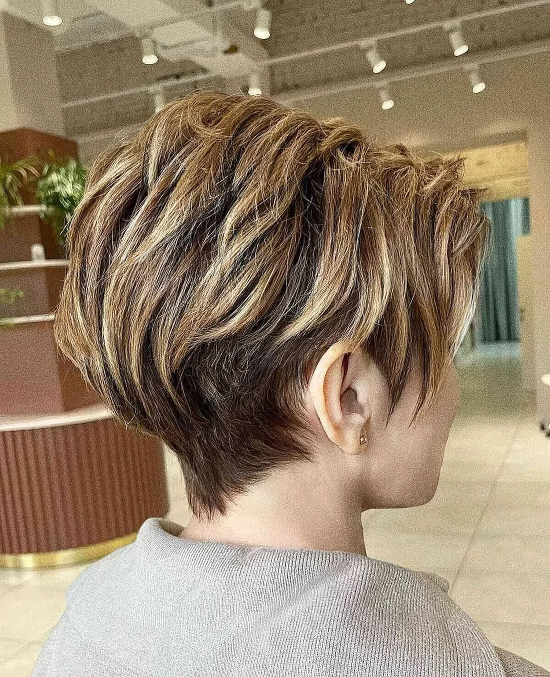 Long layered pixie with golden blonde and caramel highlights.